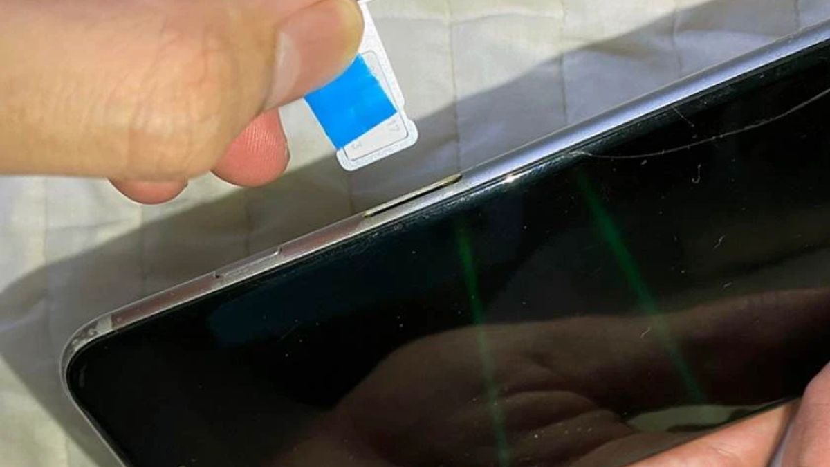 Kéo miếng nhựa ra cùng với khay sim, minh họa cách tháo khay sim khi bị kẹt bằng nhựa mỏng an toàn