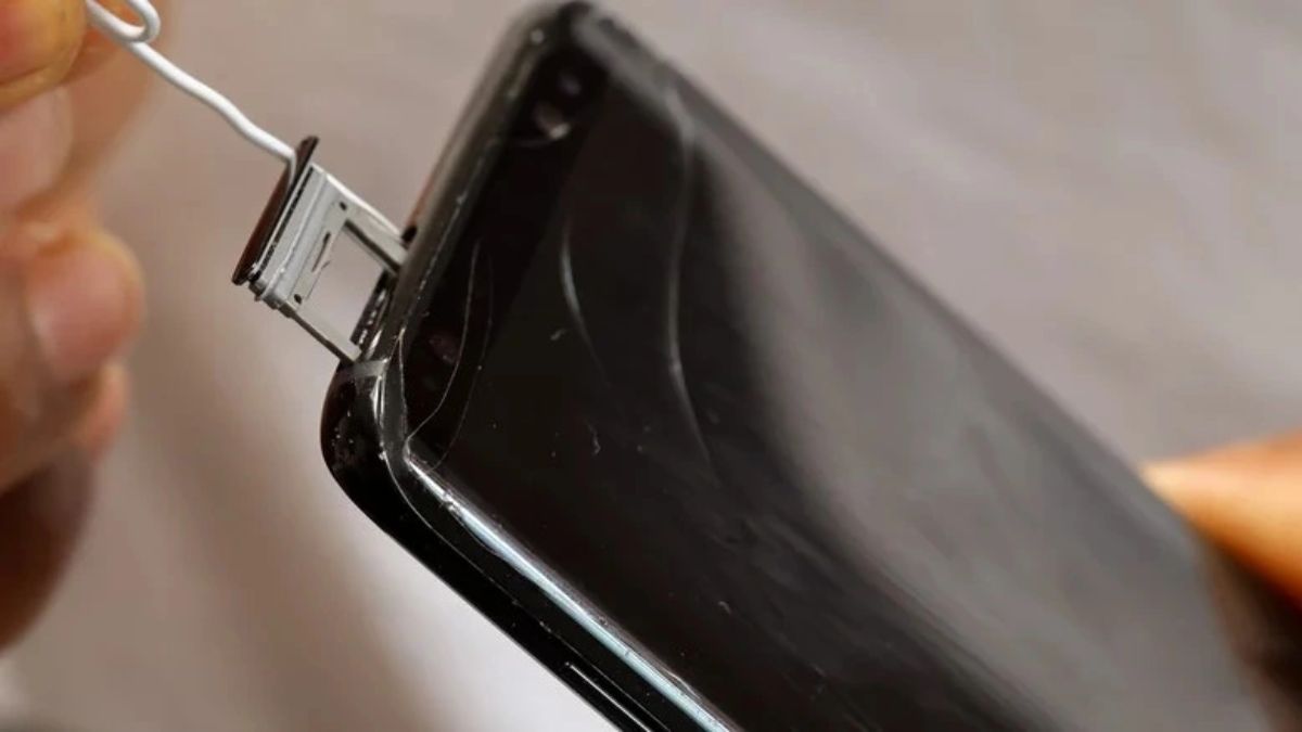 Khay sim đang được đẩy ra một phần nhờ kẹp giấy minh họa cách tháo khay sim khi bị kẹt bằng vật dụng kim loại nhỏ