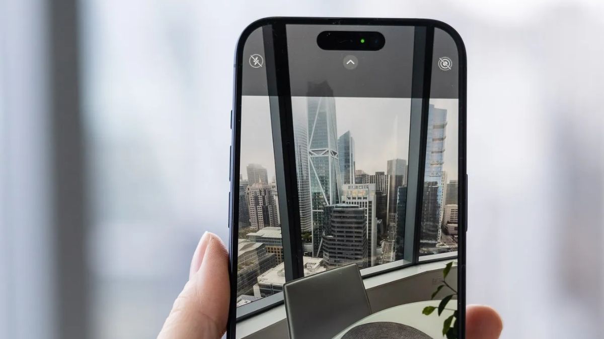 Hình ảnh tay đang cầm khăn microfiber vệ sinh camera, mẹo phòng ngừa iPhone 15 Pro Max chụp ảnh bị mờ.