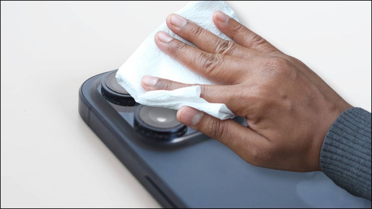 Thao tác vệ sinh ống kính camera bằng khăn microfiber, giải pháp khắc phục camera iPhone 15 Pro Max bị mờ.