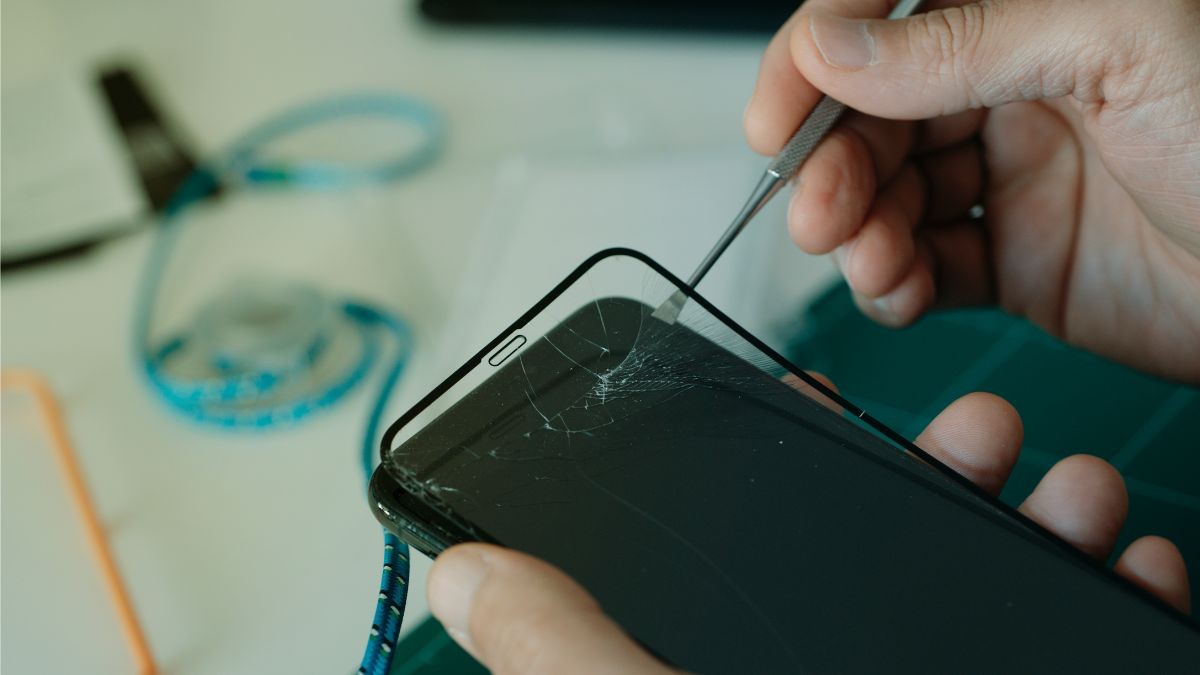 Ảnh cận cảnh thao tác tháo kính cường lực bị nứt để kiểm tra và khắc phục lỗi iphone bị đơ cảm ứng.