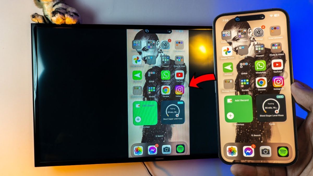 ột chiếc iPhone đang hiển thị màn hình chính, với hình ảnh phản chiếu hoàn hảo trên chiếc TV lớn bên cạnh, minh họa rõ nét cách bật chế độ screen mirroring để phản chiếu màn hình điện thoại sang TV.
