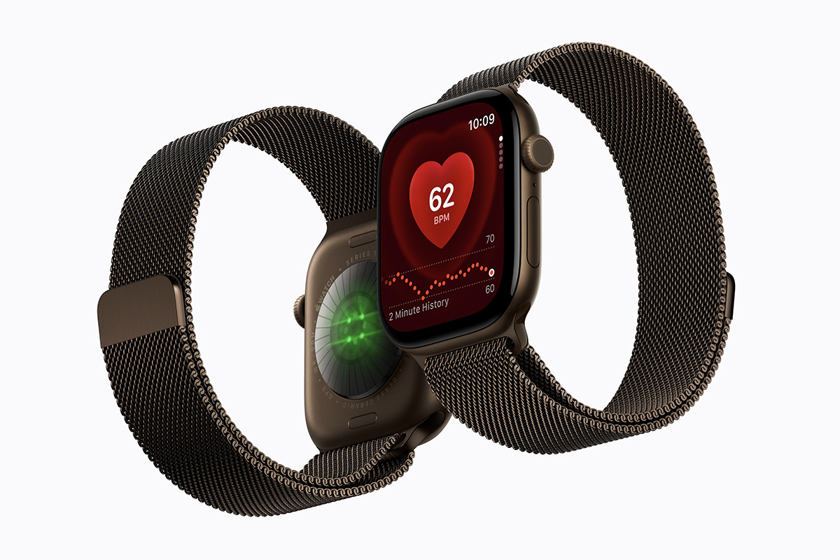 Two Apple Watch Series 12 devices are pictured side by side, with the sensors shown on the back of one and the Heart Rate app shown on the face of the other.
